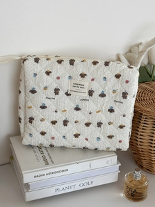 Detail of cream quilted makeup bag featuring cartoon puppy patterns and zipper closure