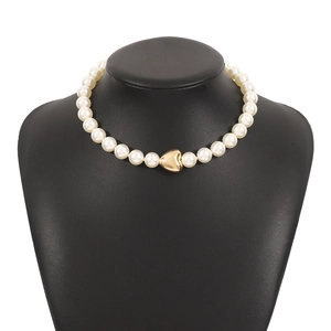 Detailed close-up of a pearl necklace with a polished gold heart pendant on a display