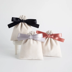 Cream velvet drawstring jewelry pouch with satin bow ribbon in elegant tiered arrangement