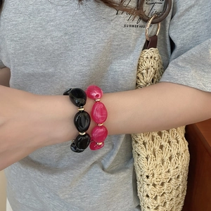 Close-up of irregular black and rose pink acrylic beaded bracelets with gold spacers