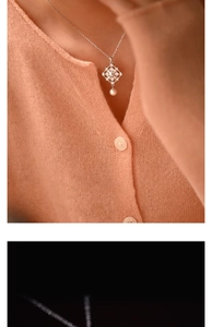 Detail of vintage silver hollow pendant with pearls worn over a beige knit cardigan