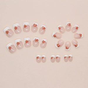 Detailed flat lay of cream French tip nails with red sequin maple leaf patterns