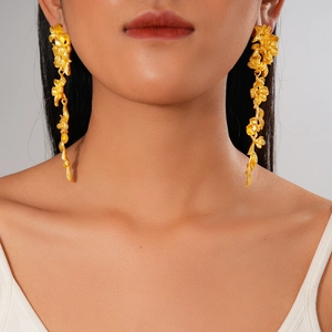 Détail de grandes boucles d'oreilles dorées en forme de fleurs et feuilles style rétro