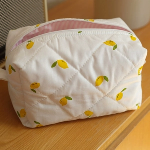 Detailed view of quilted velvet toiletry bag with yellow lemon print and striped lining