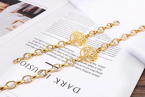 Dettaglio di due bracciali a catena dorata con ciondoli a forma di albero della vita