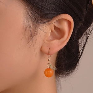 Creative orange fruit drop earrings with matte finish and gold leaf detail on model