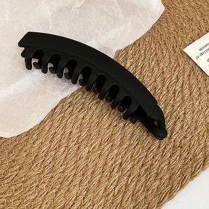 Gros plan sur la pince banane en acrylique noir mat avec dents entrelacées et forme courbe