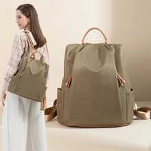 Detail of army green nylon backpack with brown leather handles and gold-tone hardware