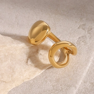 Anello aperto irregolare in acciaio placcato oro 18k esposto su una base di pietra