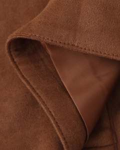 Vue macro montrant la texture du daim marron et la doublure en satin lisse avec couture