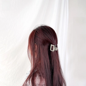 Detail view of a matte grey square claw clip styled in long reddish-brown hair
