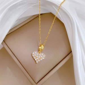 Detail der goldenen Herz-Halskette aus Titanstahl mit glitzernden Kristallen auf Seide