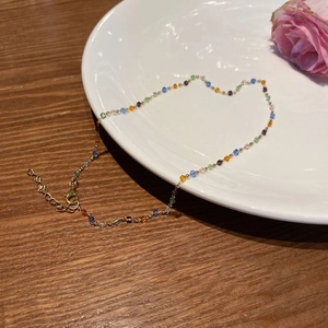 Colorful cube crystal beaded necklace with gold chain displayed on white porcelain plate