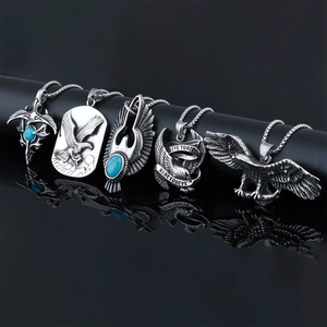 Detail of five silver eagle necklaces with turquoise stones on black reflective surface