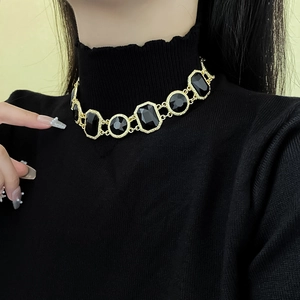 Model wearing a vintage gold necklace with geometric black gemstones and polished finish