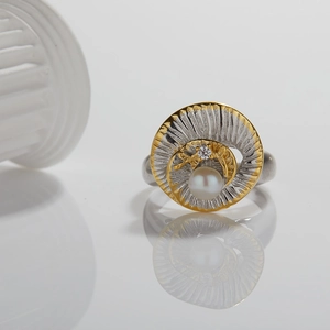 Macro shot of silver and gold spiral ring with pearl inlay on a reflective base
