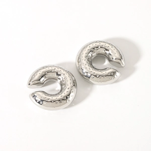 Macro view of C-shaped silver hammered texture clip-on earrings on white background