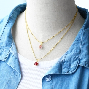 Double-layered gold beaded star necklace with pink and red star pendants on a model