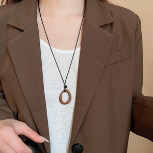 Gros plan du pendentif ovale en résine marron avec cordon noir porté par un mannequin