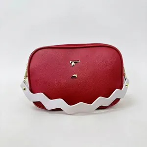 Red and white crossbody camera bag with wavy strap and golden geometric hardware
