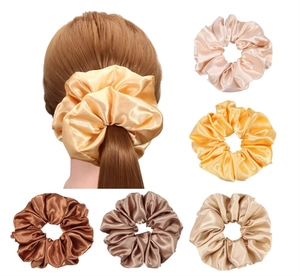 Detail of oversized satin scrunchies in various earth tones with elegant silky sheen texture