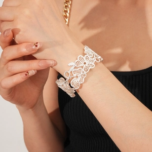 Detail eines silbernen, hohlen Spitzen-Blumenarmbands mit feinem floralem Muster