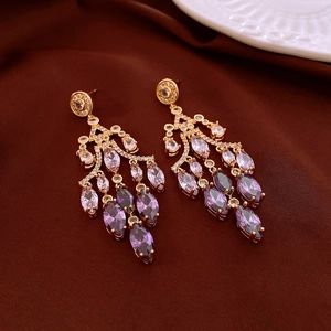 Detail of vintage gold flower earrings with purple gemstones and long tassels
