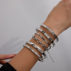 Stack of silver stainless steel bracelets featuring hammered textures and link chains