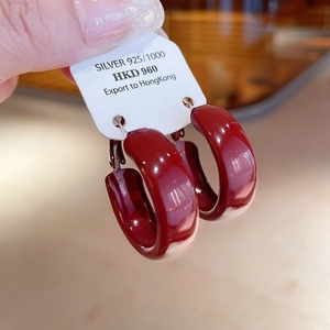 Detailed close-up of dark red enamel C-shaped earrings with 925 silver studs