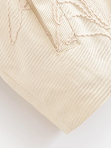 Vue détaillée du tissu sergé beige avec broderie 3D sophistiquée et coutures précises