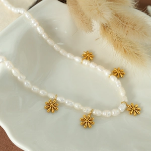 French style freshwater pearl necklace with gold daisy pendants on a white ceramic plate