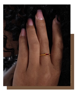 Close-up of thin gold titanium steel ring with rectangular red zircon on model's finger