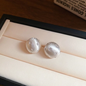 Macro view of brushed silver star earrings with inlaid rhinestones and sphere shape
