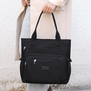 Grand sac fourre-tout noir en nylon avec plusieurs poches, tenu par un mannequin élégant