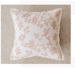 Detail of floral jacquard cushion cover with pink blossoms on cream knitted fabric