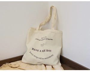 Macro detail of beige canvas tote bag with black slogan print on a cozy blanket
