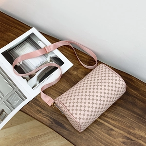 Nude pink cylinder shoulder bag with geometric patterns on a wooden table setup