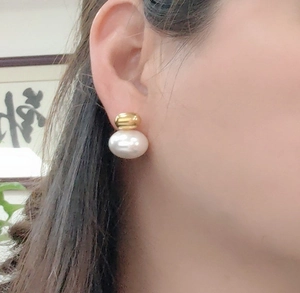 Detail of French vintage pearl stud earring on model featuring gold metal and 18K finish