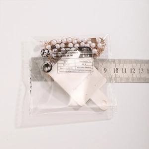 Close-up of pearl necklace with gold chain next to a ruler for size measurement
