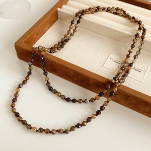 Detail of faceted agate beads on a bohemian long strand necklace with warm amber tones
