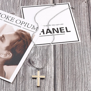 Close-up of dual-tone cross pendant with gold frosted finish on silver metal chain