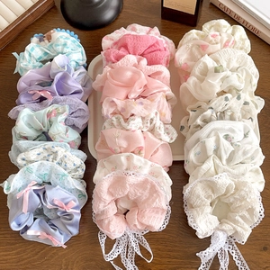 Set of 21 floral lace scrunchies in pastel colors arranged on a wooden surface