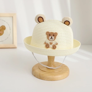 Detailed texture of kids straw hat with 3D bear ears and embroidery on wooden stand