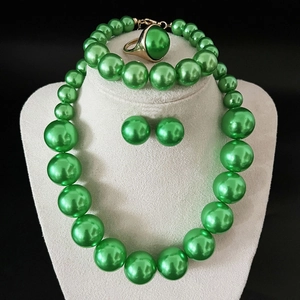 Detailed view of elegant green pearl jewelry set featuring necklace, bracelet, and earrings