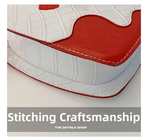 Detail of red and white faux crocodile leather handbag with precise stitching craftsmanship