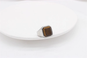 Macro shot of silver titanium steel men's signet ring with a square tiger eye gemstone