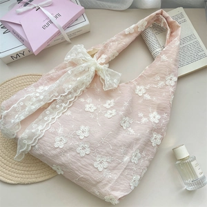 Detail of floral embroidery and large lace bow on a pink fabric tote bag