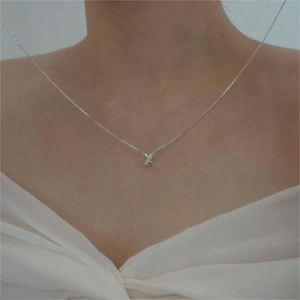 Close-up of minimalist S925 sterling silver X-shaped necklace pendant worn by a model