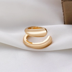 Detalle de pendiente ear cuff dorado de doble capa sobre fondo de seda blanca