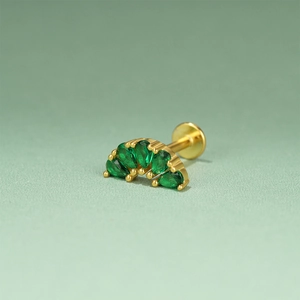 Macro shot of gold emerald flower cartilage piercing with green zircons and threaded post